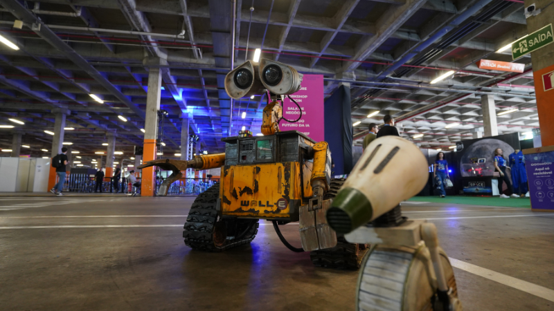 Robôs que lembram personagens do filme Wall-E no piso de um amplo espaço, no contexto do evento Campus Party em Goiás, Brasil.